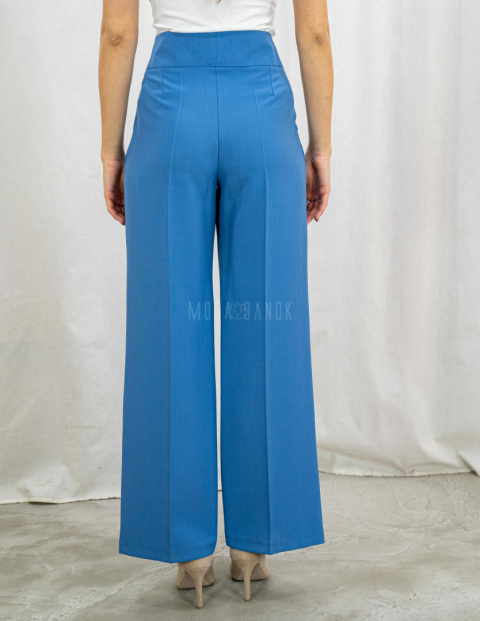 Jasnoniebieskie eleganckie spodnie damskie z szeroką nogawką i rzędowymi guzikami CORALLINE- MODA SANOK Jasnoniebieskie eleganckie spodnie damskie z szeroką nogawką i rzędowymi guzikami CORALLINE- MODA SANOK